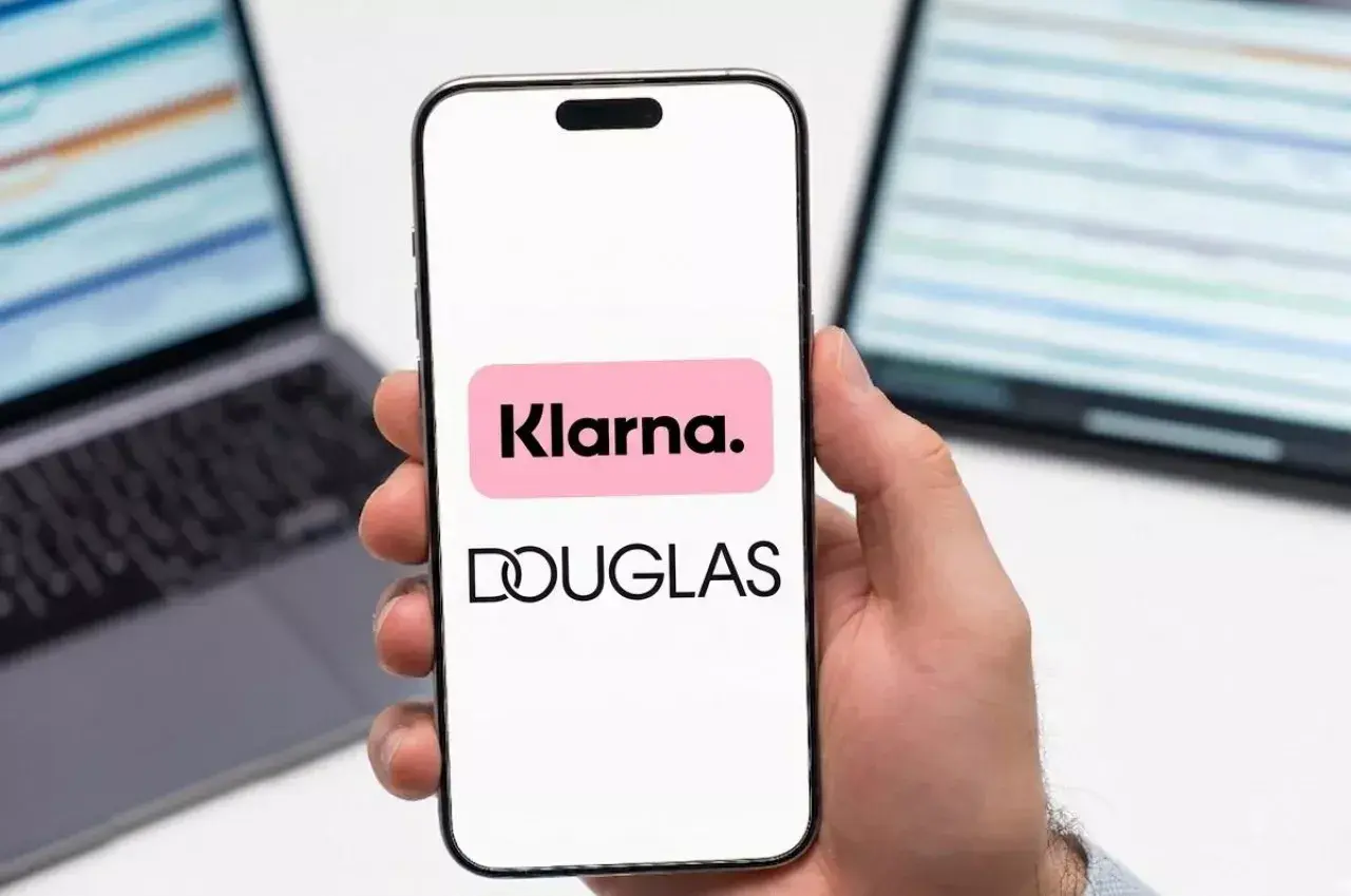 Dłoń trzyma smartfon z logo Klarna i Douglas. To ułatwia zakupy, jak douglas paypo.