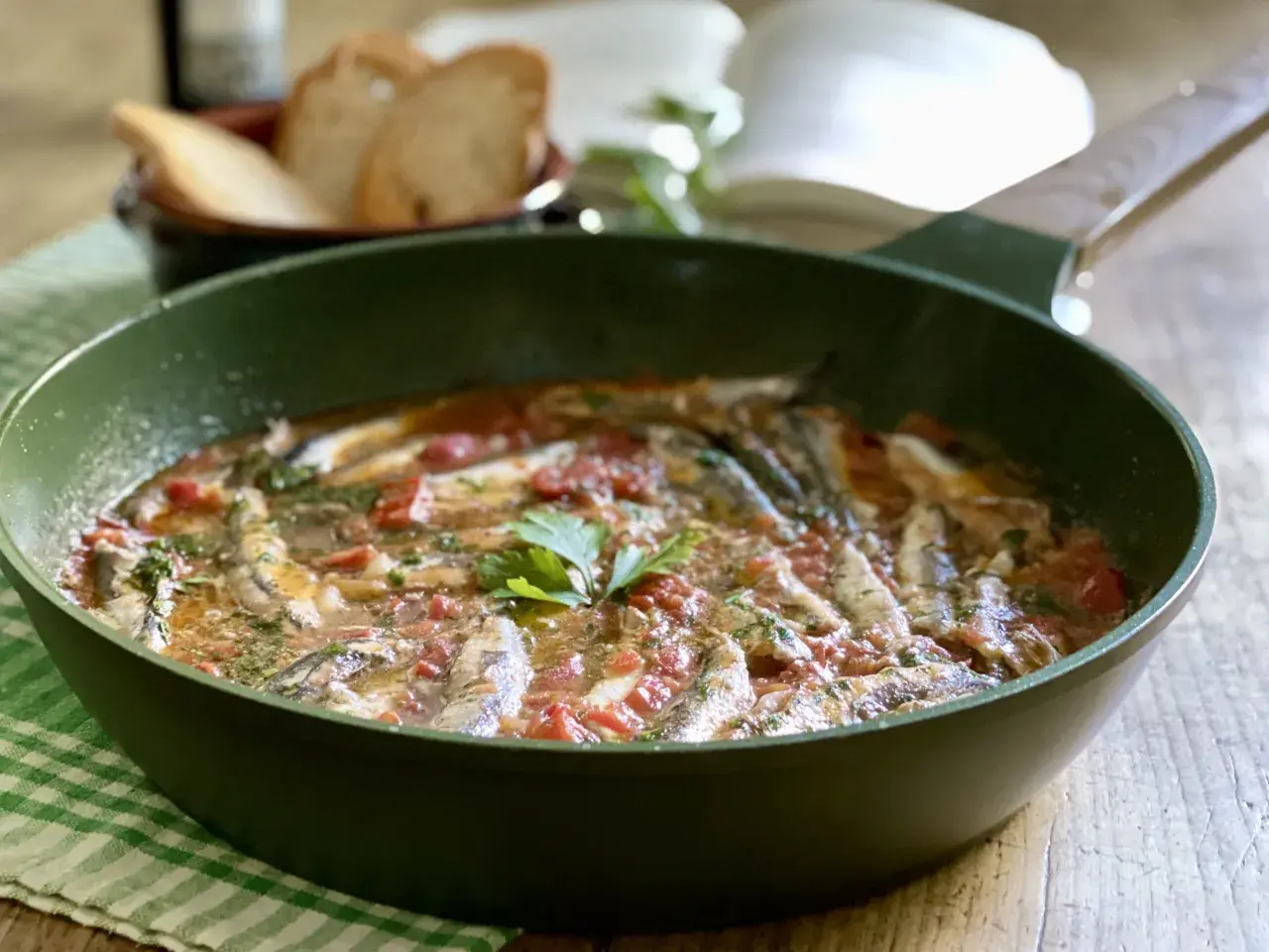 Un saporito bagnun di acciughe in padella, con pomodoro e prezzemolo, pronto per essere gustato con pane tostato.