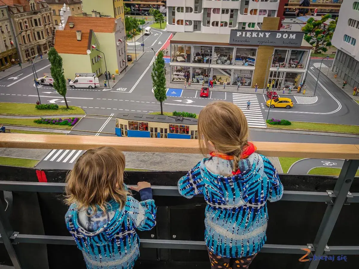 Dwie dziewczynki podziwiają miniaturowe miasto, gdzie znajdują się sky tower atrakcje dla dzieci.