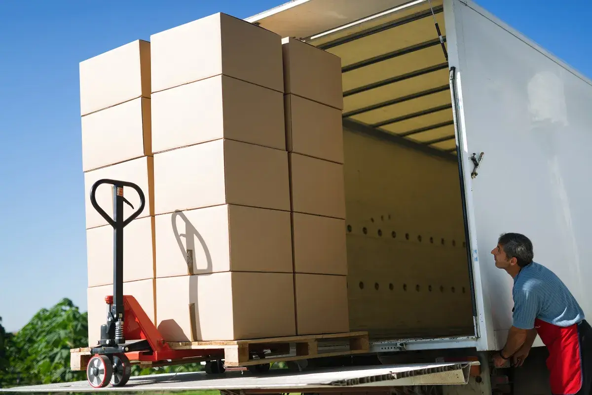 Pracownik ładuje paletę z kartonami do ciężarówki. Efektywny transport drobnicowy Polska.
