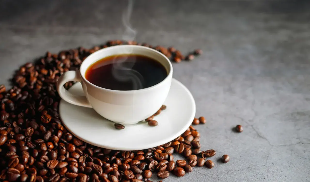 Gorące espresso otoczone ziarnami kawy. Pyszny napój, który ma znikome espresso kalorie.