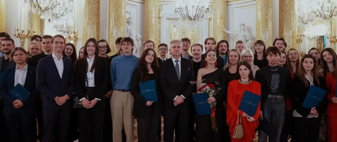 Grupa młodych ludzi w eleganckich strojach odbiera stypendium artystyczne ministra kultury.