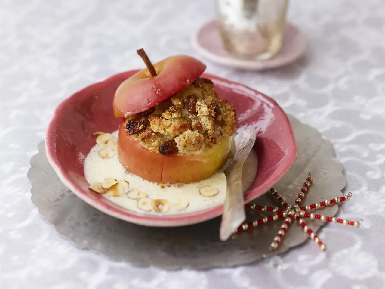 Ein köstlicher, veganer Bratapfel mit knuspriger Füllung und cremiger Soße, garniert mit Mandelsplittern.