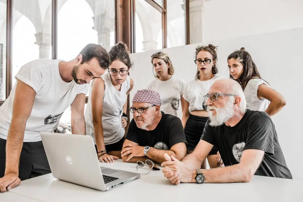 Stefano Guindani e un gruppo di giovani analizzano un progetto al computer, concentrati e seri.