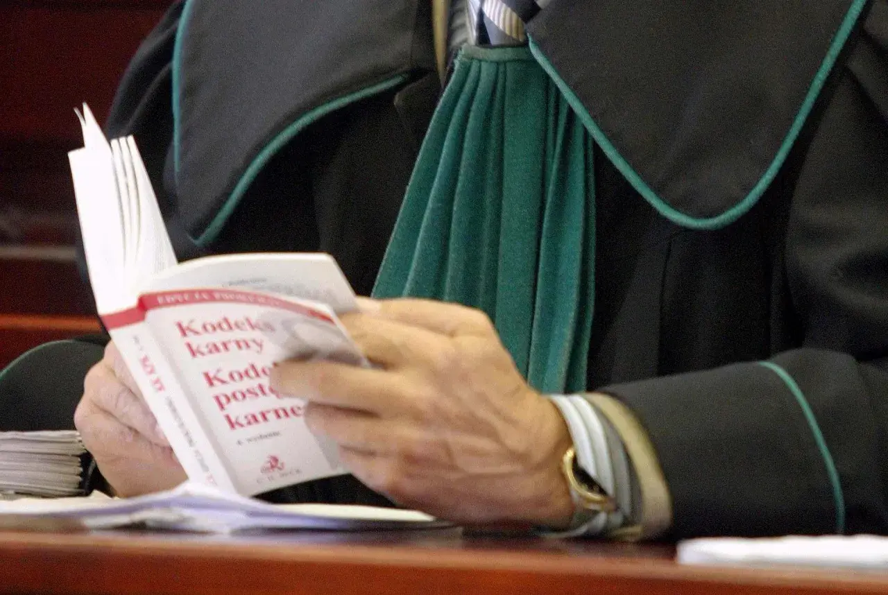 Prawnik w todze czyta Kodeks karny.