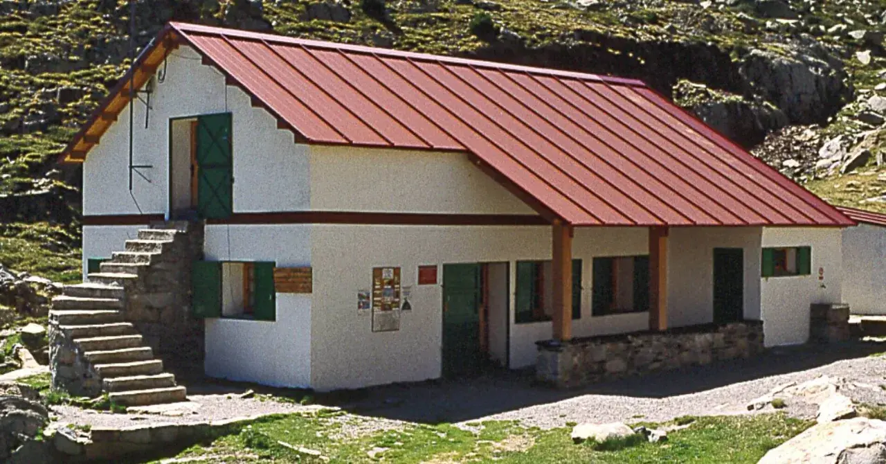 Un refugio de montaña en Cataluña, con tejado rojo y escaleras de piedra.