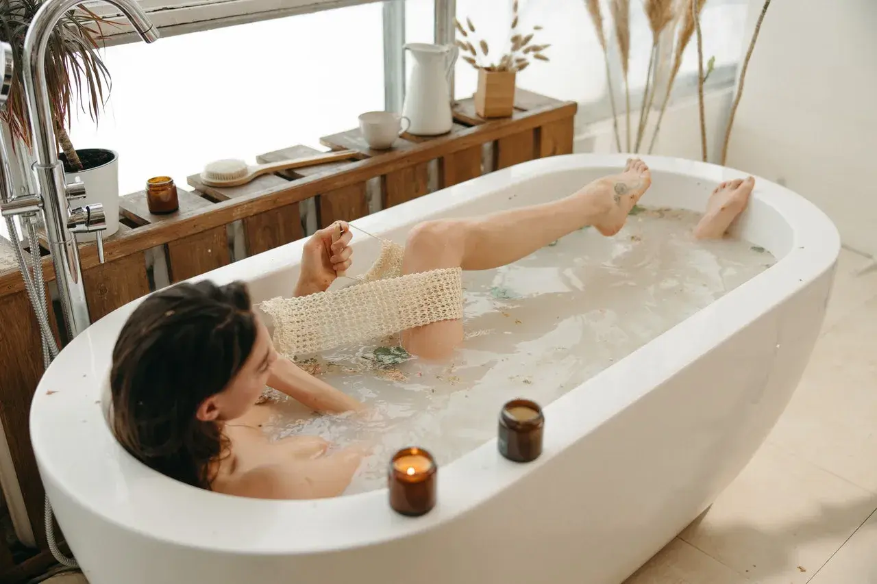 Relaks w wannie z naturalnymi kosmetykami. Półka nad wanną inspiracje: świece, zioła, szczotka do kąpieli.