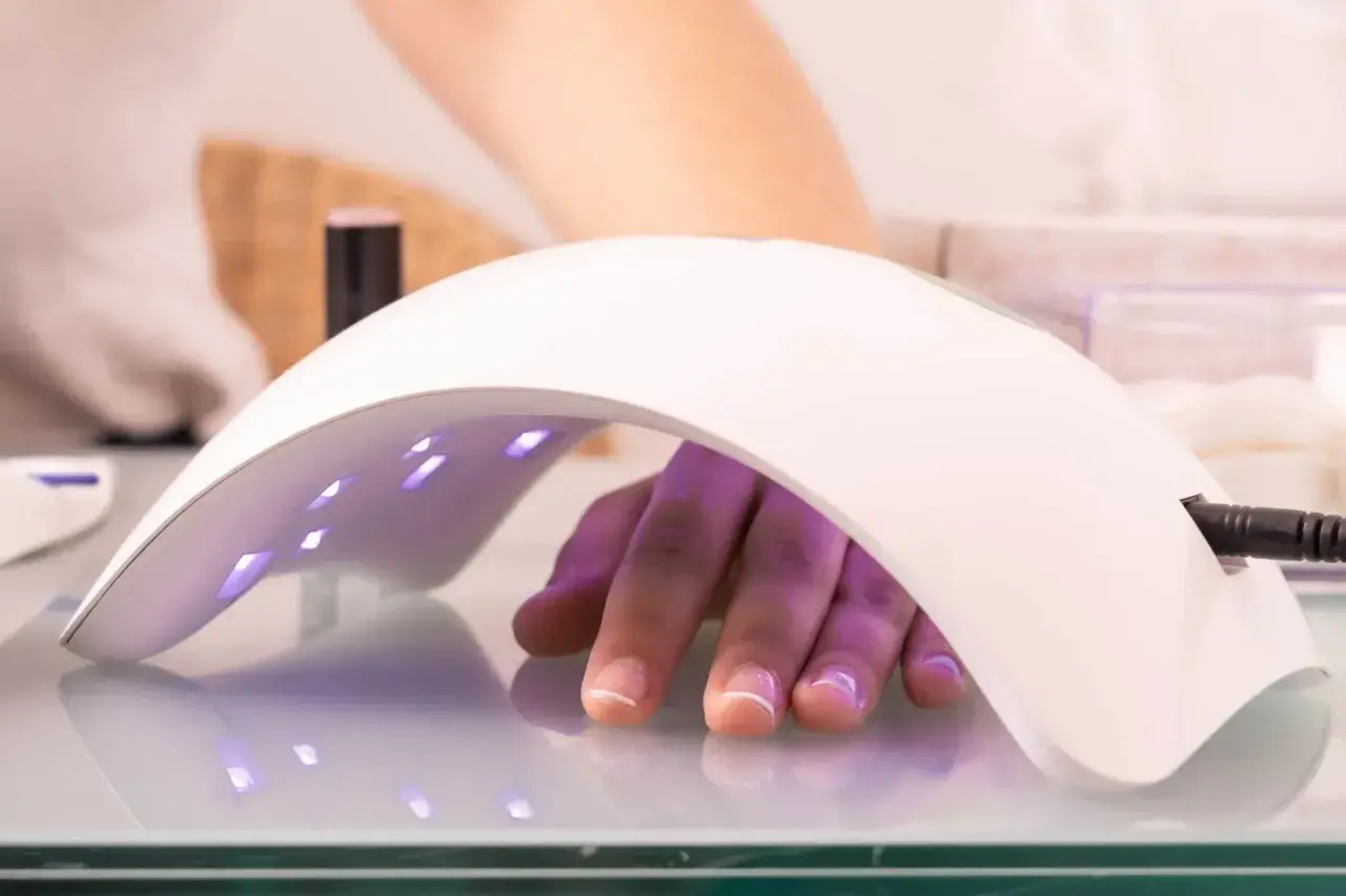 Dłoń pod lampą LED 48W, utwardzanie żelu. Ile utwardzać żel w lampie led 48w? Czas zależy od produktu.
