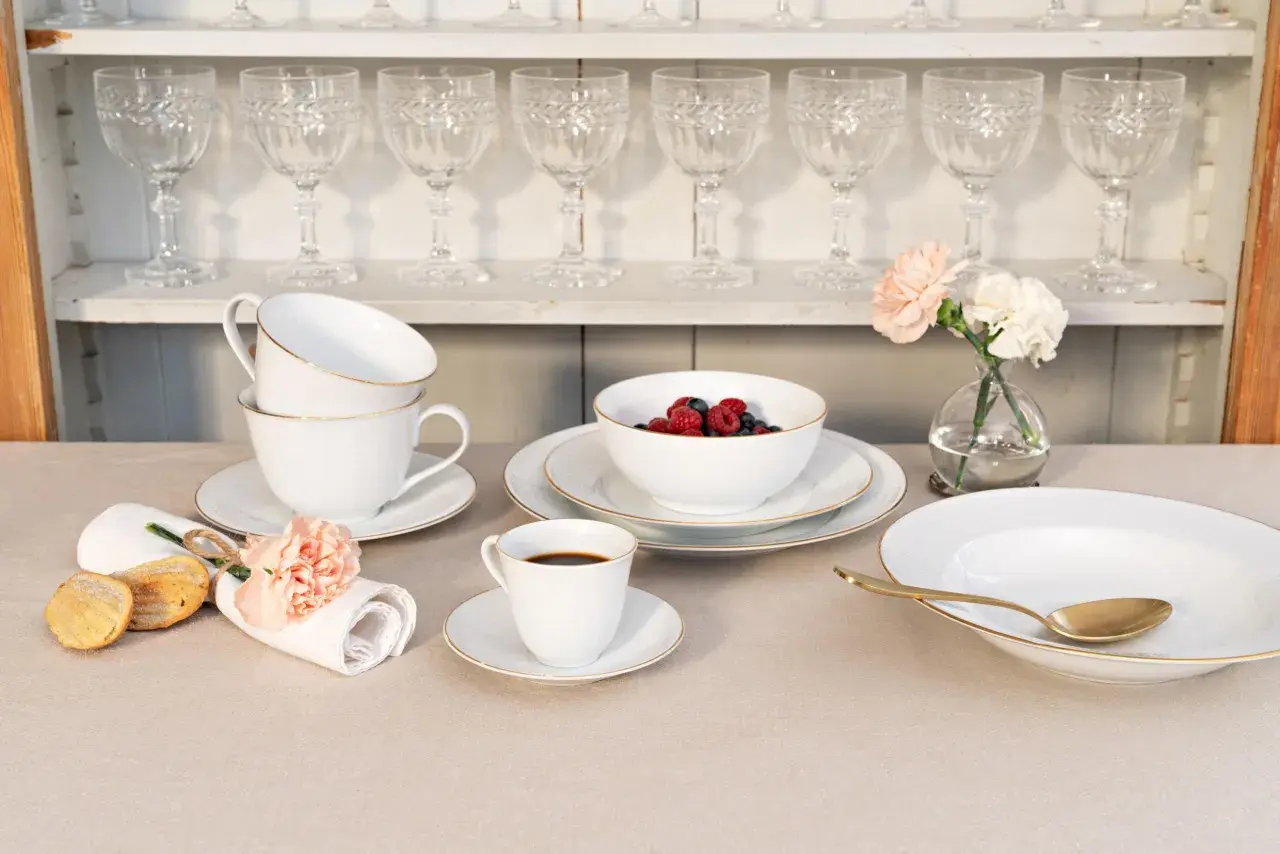 Elegantes schwedisches Porzellan mit goldenen Akzenten, serviert mit Beeren, Kaffee und Gebäck.