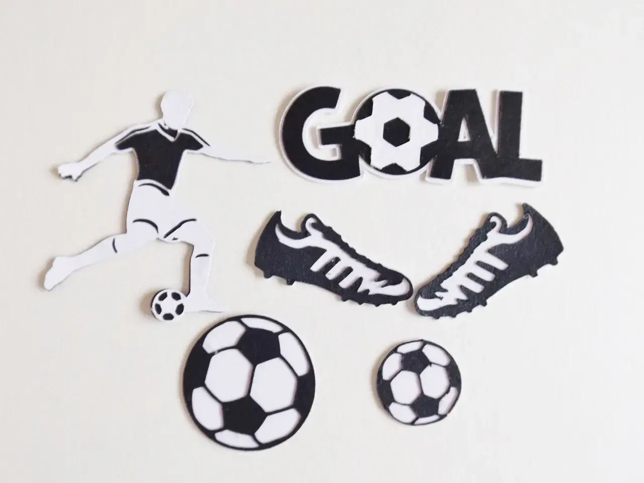 Silueta de futbolista pateando balón, dos botas, tres balones y la palabra "GOAL" en manualidades de fútbol.