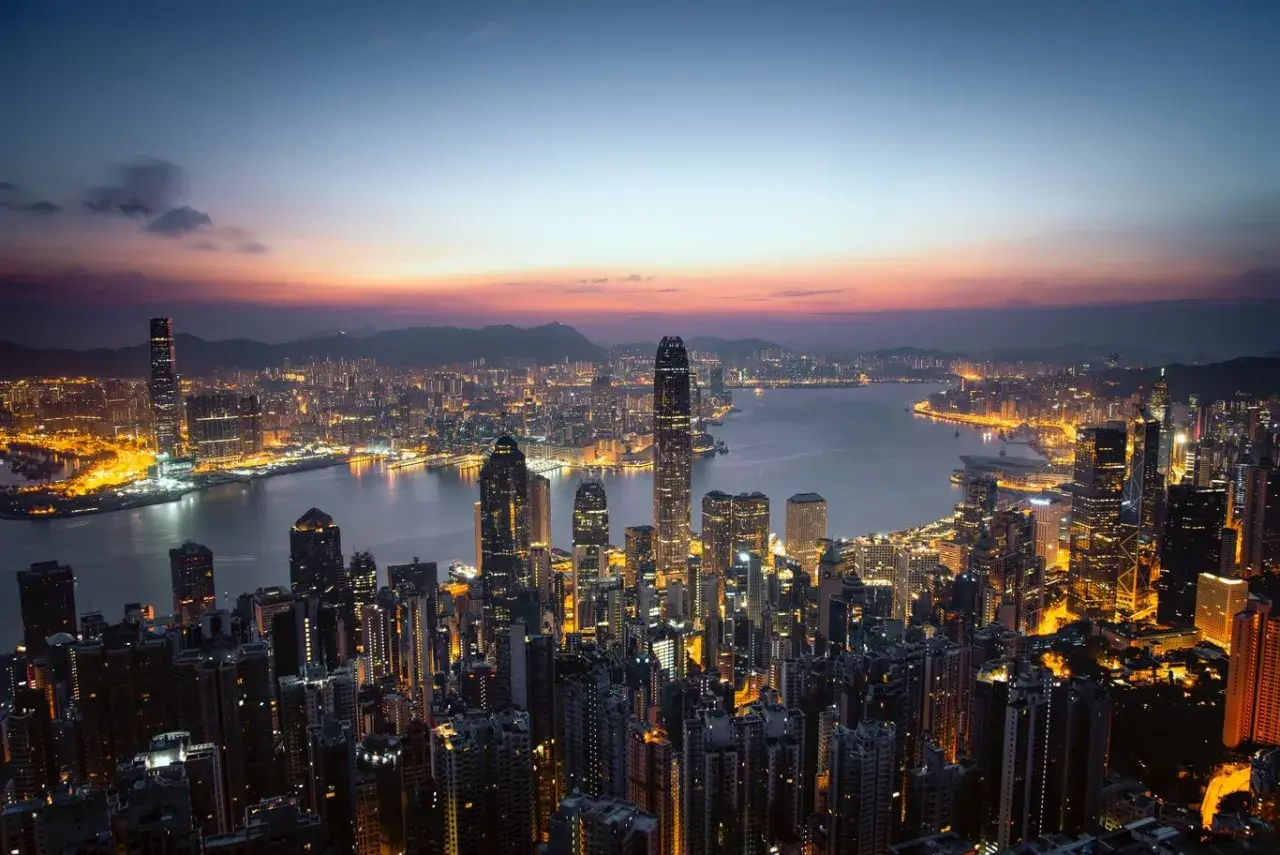 Wieczorny widok na rozświetlony Hongkong. Wiele wieżowców lśni światłami, tworząc niesamowity krajobraz. Ciekawe fakty o tym mieście można odkrywać, podziwiając jego panoramę.