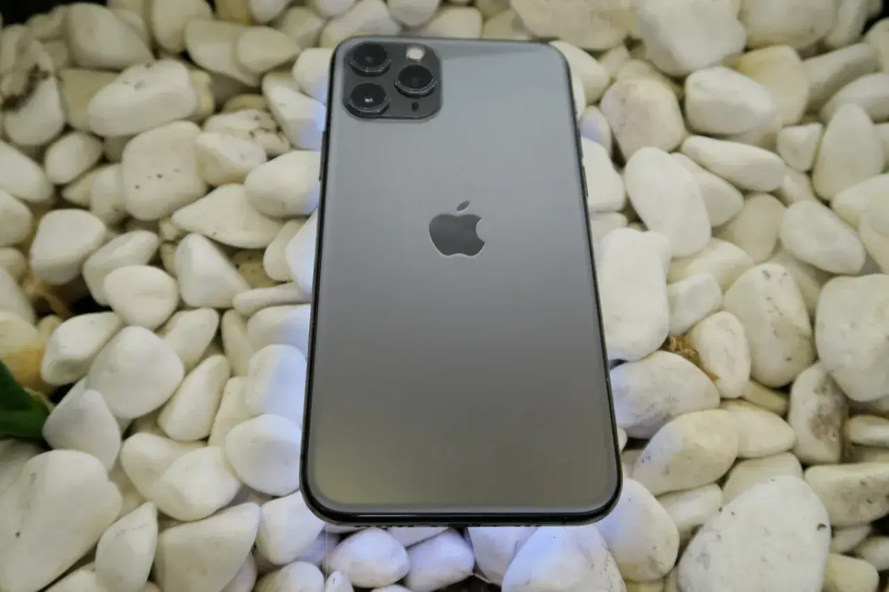 Szary iPhone 11 Pro leży na białych kamieniach. To urządzenie iPhone niedostępne, ale wciąż piękne.