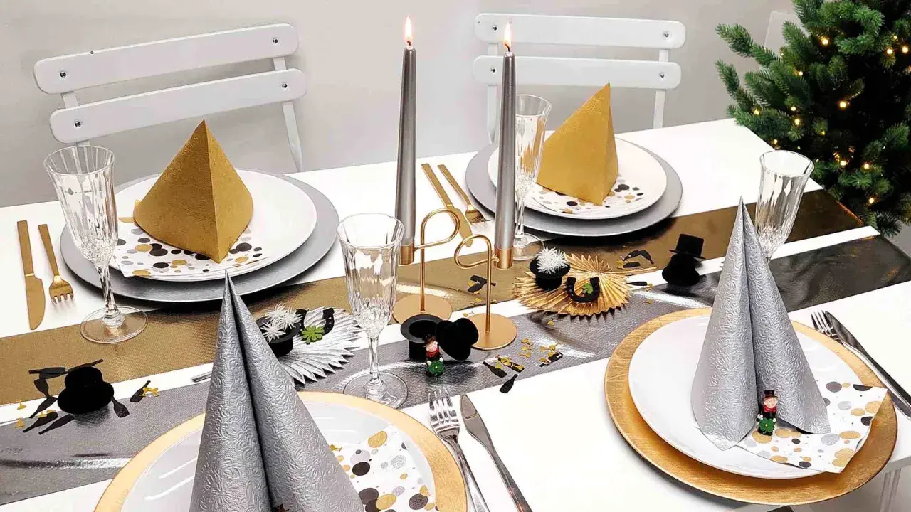 Festlich gedeckter Tisch mit Kerzen, Gläsern und Servietten in Gold und Silber. Eine tolle Silvester Idee für eine glamouröse Feier.