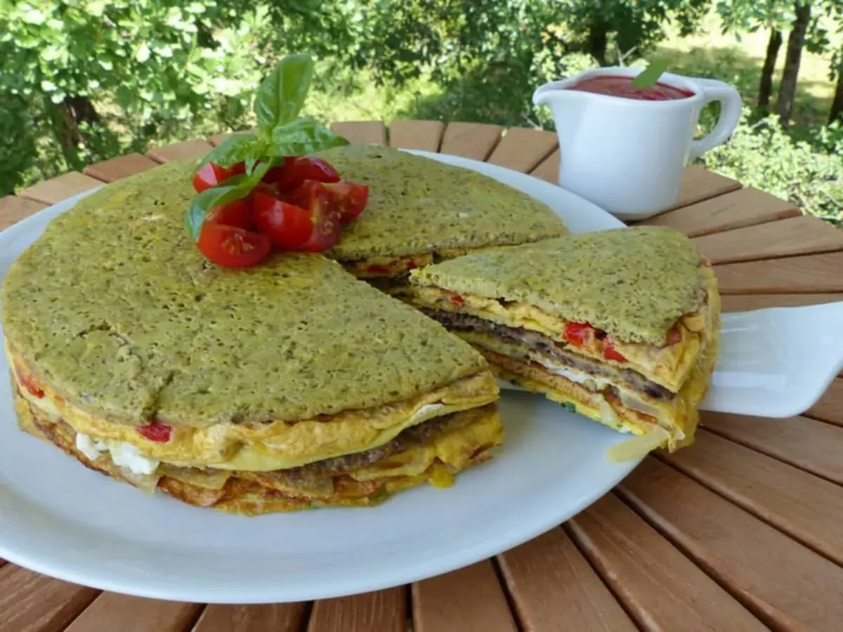 Le crespeou, une tourte verte aux couches d'omelette et de légumes, garnie de tomates et de basilic.