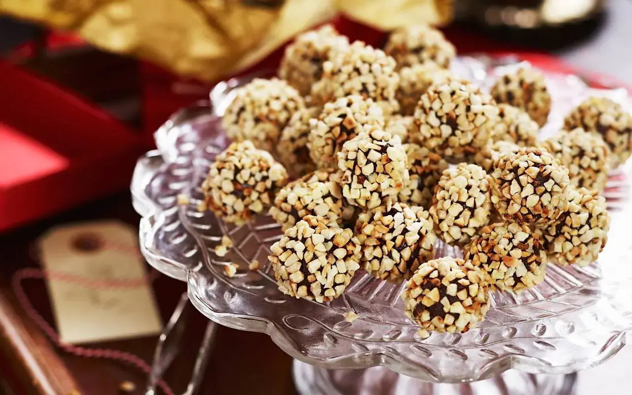 En hög med chokladtryffel täckta av hackade nötter på ett glasfat. Perfekt för fikat eller som en gåva.