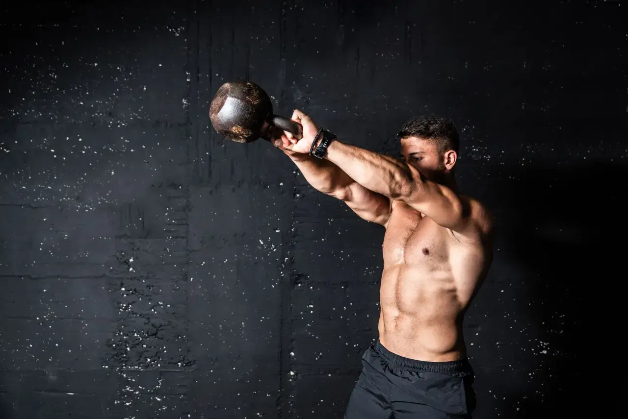 Mężczyzna ćwiczy z kettlebell. Intensywny trening, który pokazuje, co to znaczy wysiłek anaerobowy.