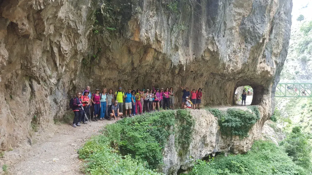 Grupo de excursionistas posa en la Ruta del Cares, superando la dificultad del terreno rocoso y los túneles.