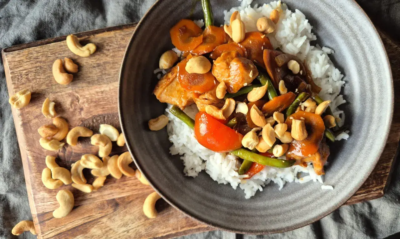 En skål med ris toppad med kyckling, grönsaker och krispiga kyckling cashew.
