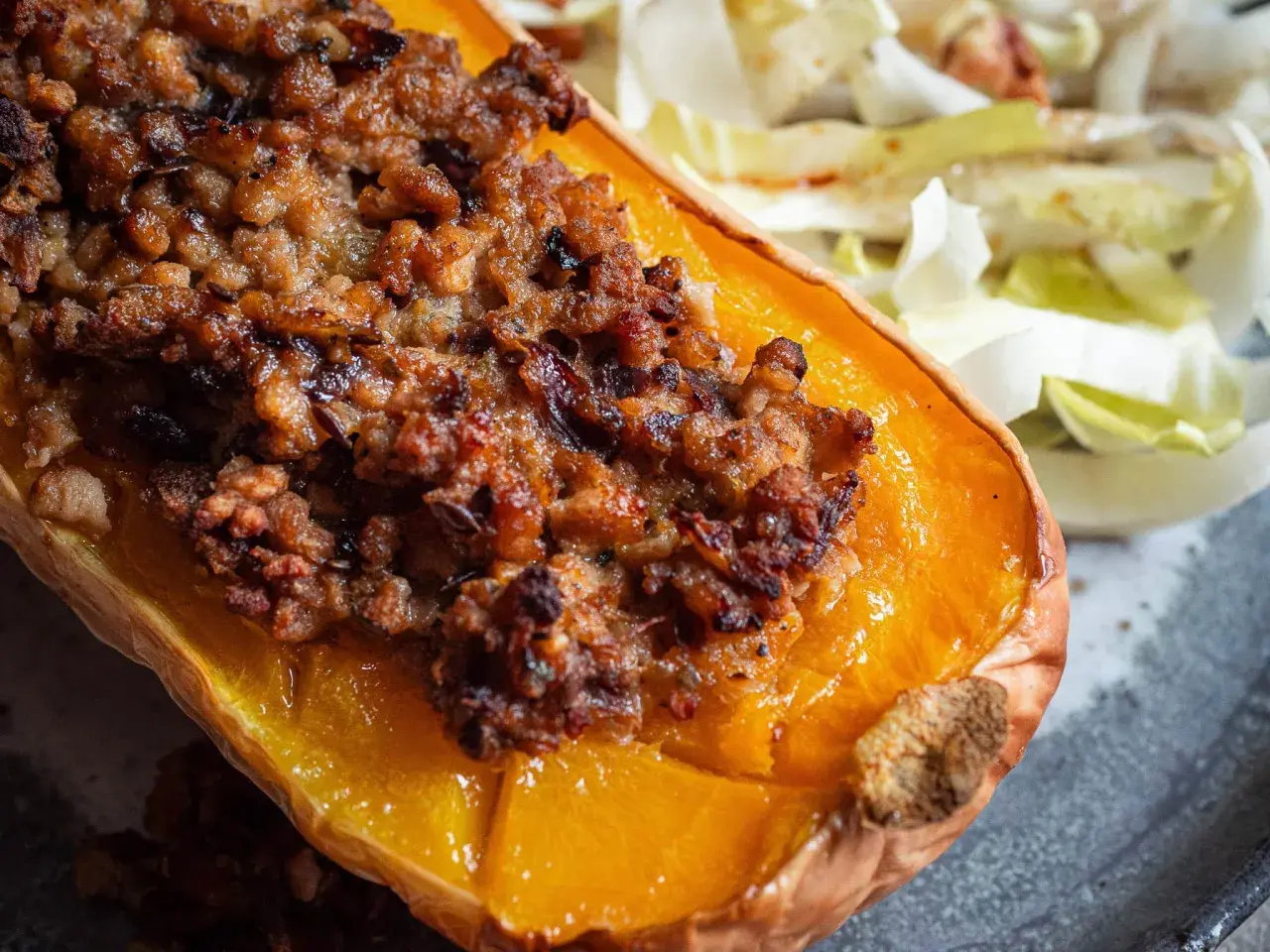 Moitié de courge butternut farcie, une recette savoureuse avec une garniture dorée et croustillante, servie avec une salade fraîche.