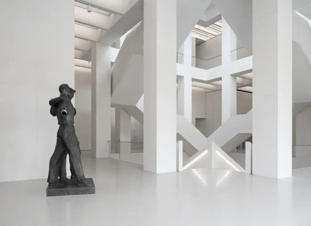 Rzeźba w nowoczesnym muzeum z betonową architekturą i schodami.