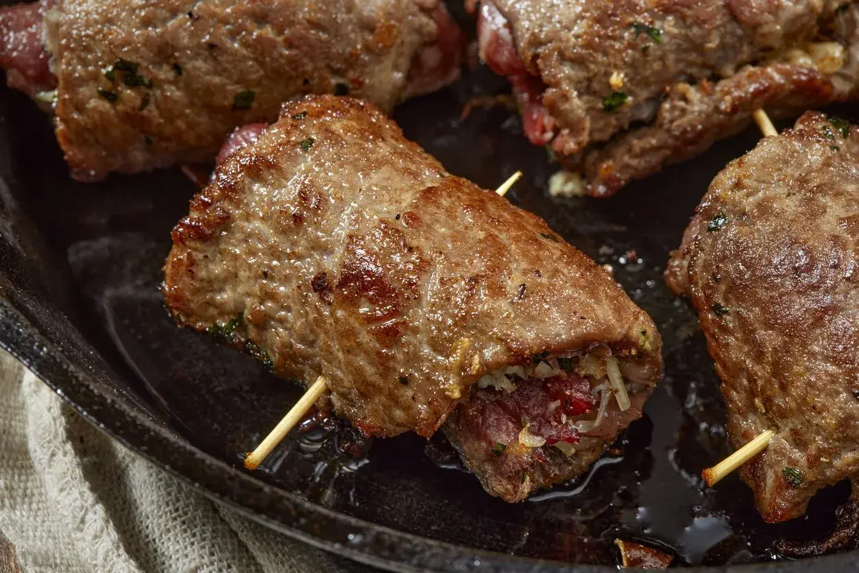 Involtini di carne succulenti, cotti in padella, con ripieno visibile e stuzzicadenti.