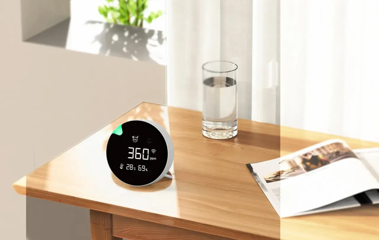 Monitor de calidad del aire muestra 360 ppm, indicando niveles de CO2 saludables en un ambiente hogareño.