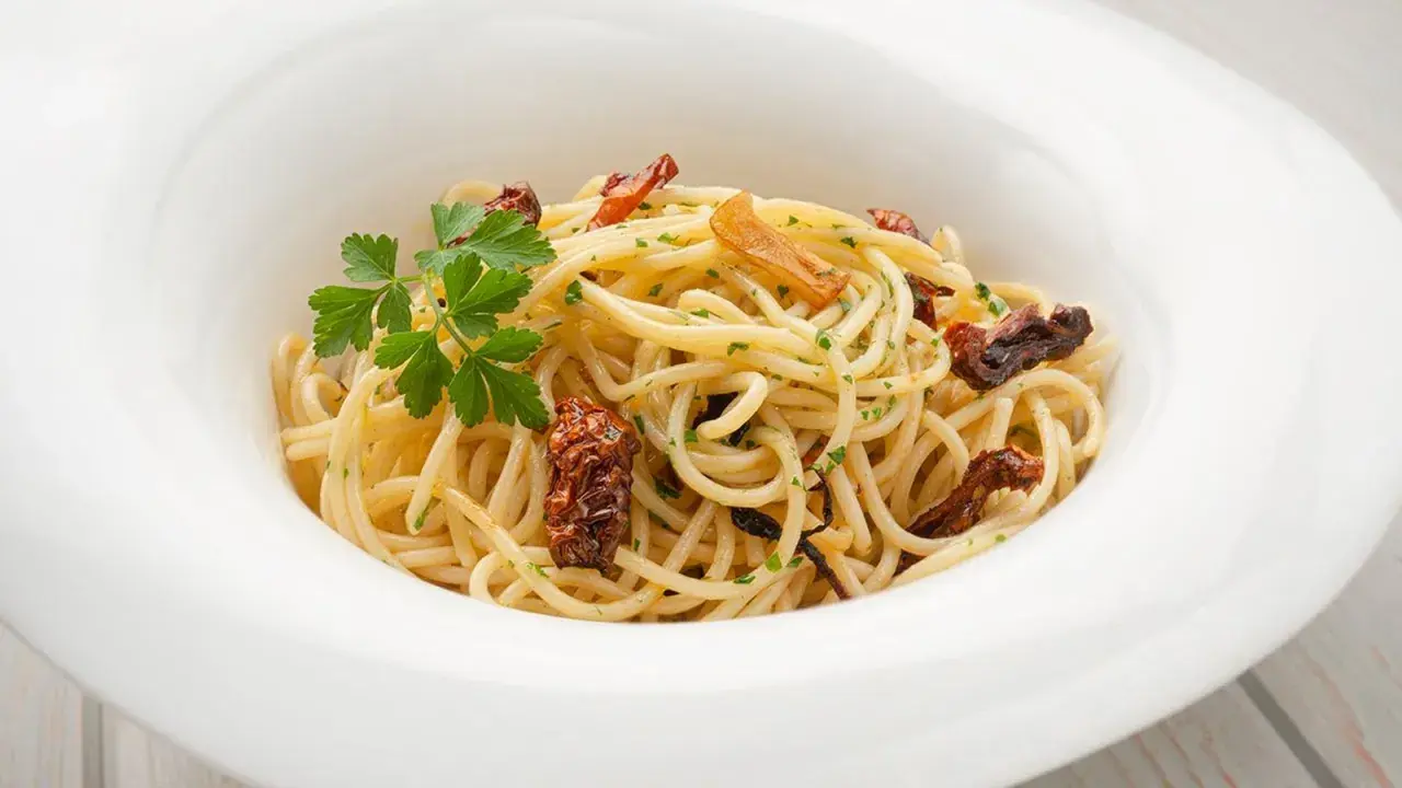 Espaguetis al ajillo, un plato sencillo pero delicioso, con pasta dorada, trozos de ajo crujiente y perejil fresco.