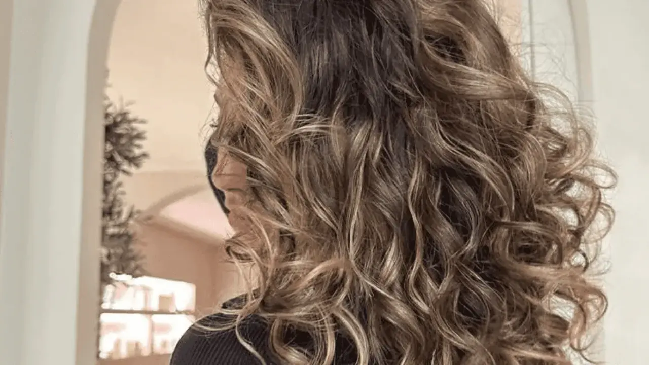 Melena castaña con mechas pelo rizado, luciendo ondas naturales y un brillo espectacular.
