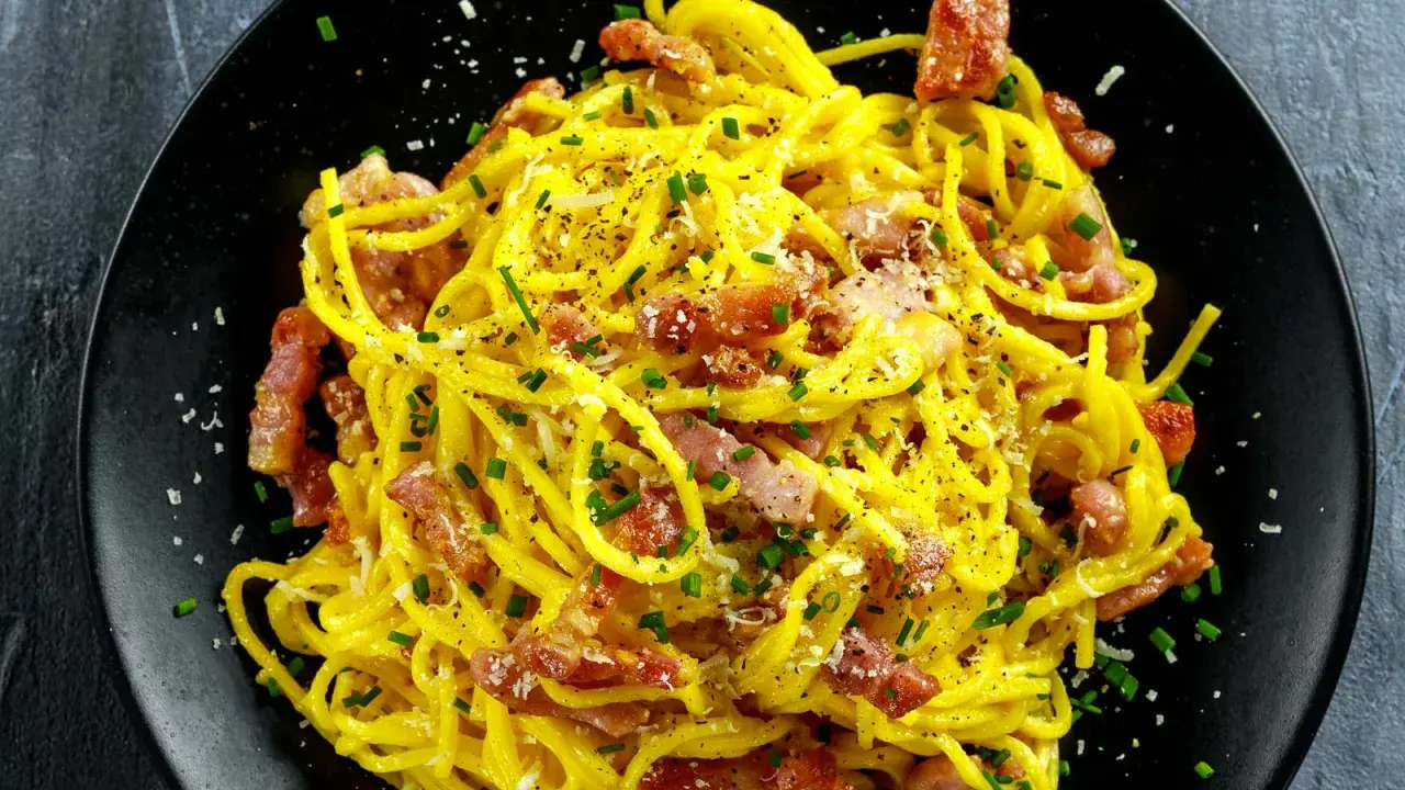 Spaghetti crémeux à la carbonara, garni de lard italien croustillant, de parmesan râpé et de ciboulette fraîche. Un délice !