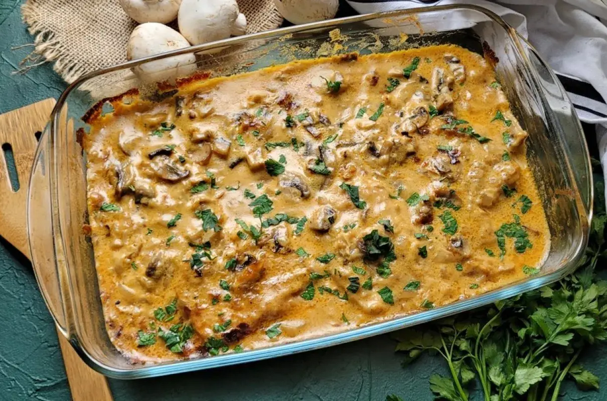 Pyszny schab w sosie pieczarkowym, zapiekany w szklanym naczyniu, posypany świeżą natką pietruszki.