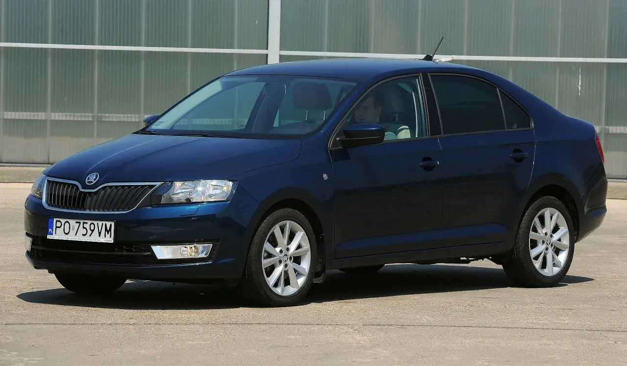 Ciemnoniebieska Skoda Rapid stoi na parkingu. Widoczny jest rozmiar opon, który idealnie pasuje do tego modelu.