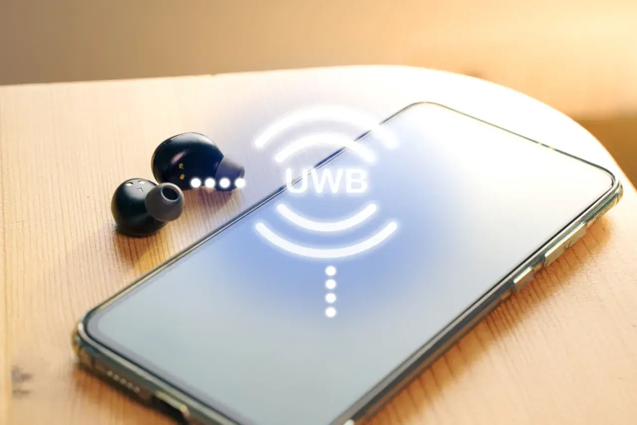 Auriculares inalámbricos y un smartphone con el símbolo UWB que es una tecnología de comunicación.