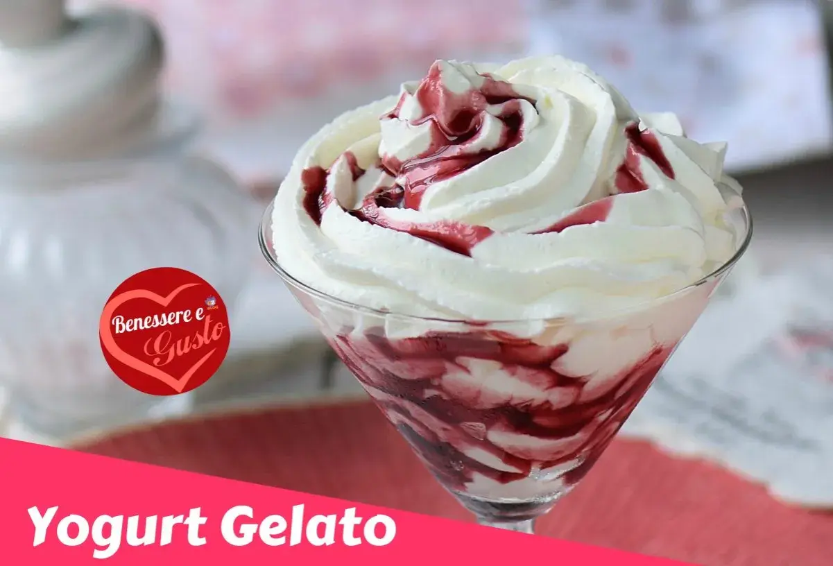 Coppa di gelato con yogurt greco e variegatura ai frutti di bosco, guarnita con panna montata.