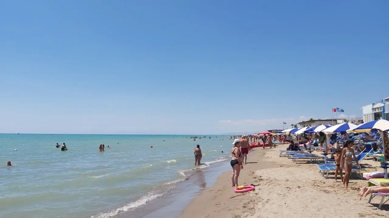 Giornata di sole al Metaponto Lido. Gente in acqua e sotto gli ombrelloni, bagnanti che si godono la spiaggia.