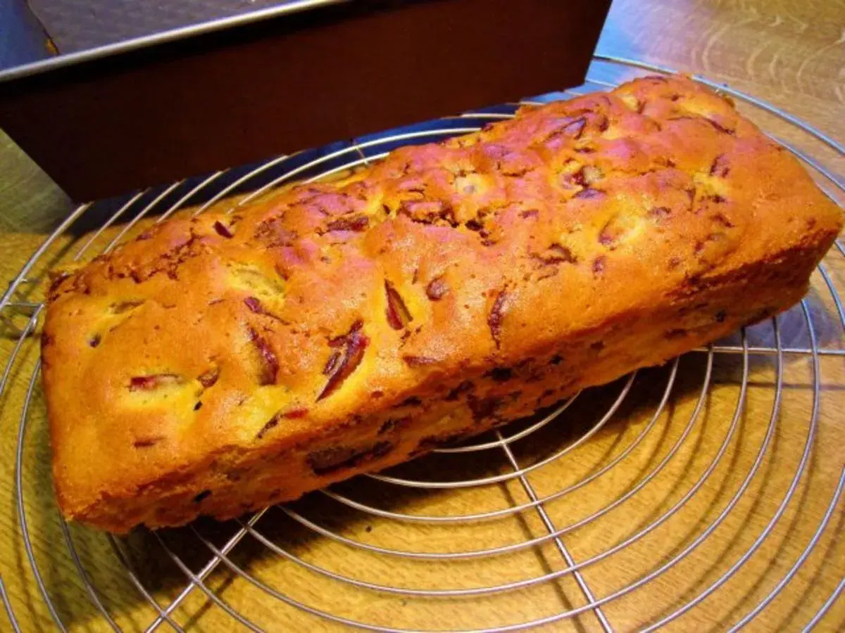 Frisch gebackener Pflaumenkuchen in Kastenform, goldbraun und mit saftigen Pflaumenstücken, kühlt auf einem Gitter ab.