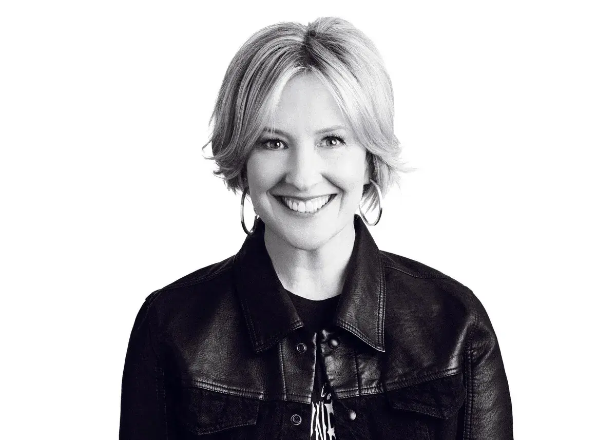 Uśmiechnięta Brené Brown w skórzanej kurtce, uosobienie odwagi i autentyczności.
