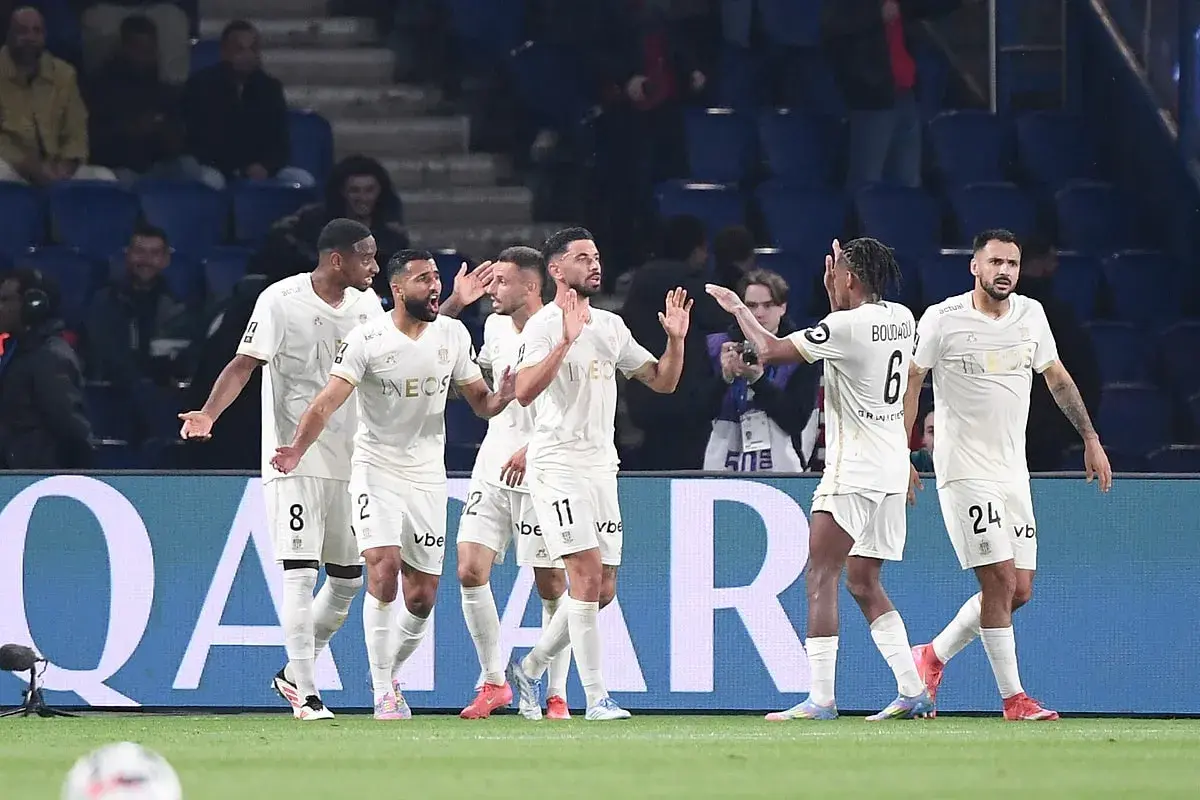 Piłkarze OGC Nice świętują bramkę przeciwko Stade de Reims. Drużyna w białych strojach z numerami 8, 2, 11, 6 i 24 cieszy się z sukcesu.