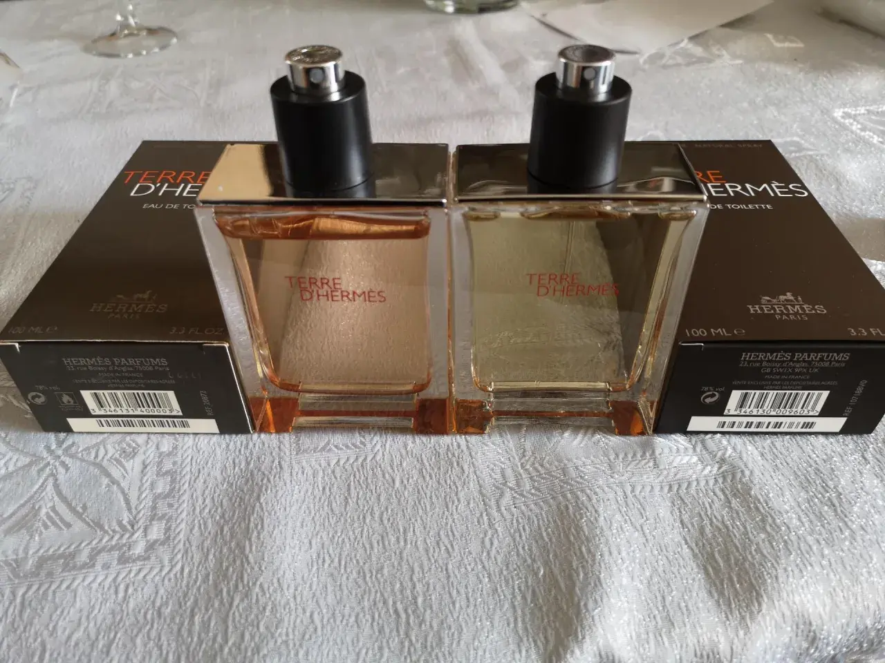 Dwa flakony Terre d'Hermès EDT, każdy 100 ml, stoją na białym obrusie.