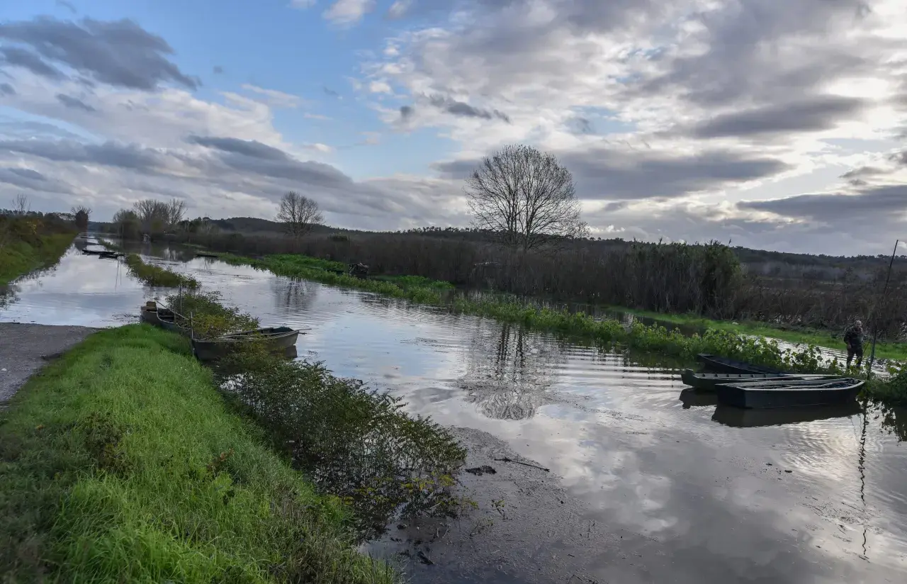 Canale con barche ormeggiate vicino a Ponte Buggianese, riflessi nel cielo nuvoloso.