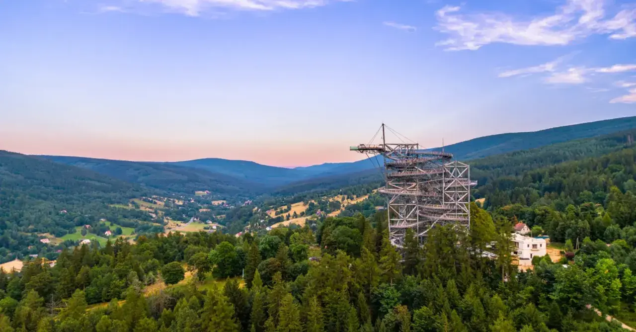 Metalowa konstrukcja sky walk wznosi się na znaczną wysokość nad zalesionymi wzgórzami, oferując zapierające dech w piersiach widoki.