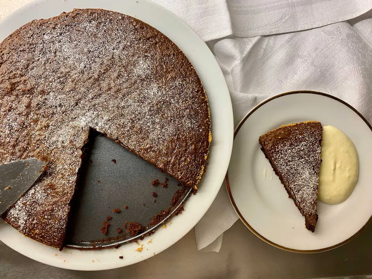 Chokladkaka med pudersocker, en bit serverad med grädde. Perfekt för att baka snabbt och enkelt.