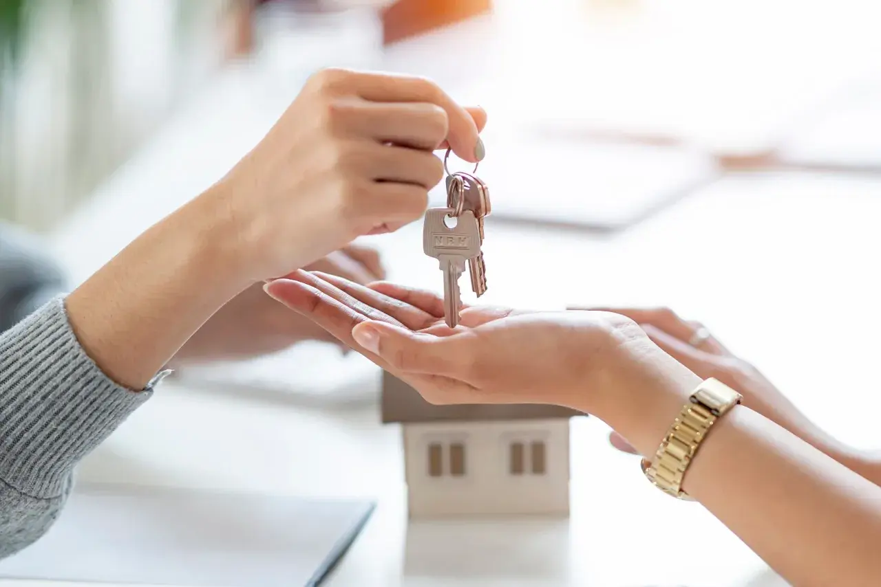 Manos intercambian llaves de una casa modelo. Un nuevo comienzo, que significa cru, se materializa en este momento.