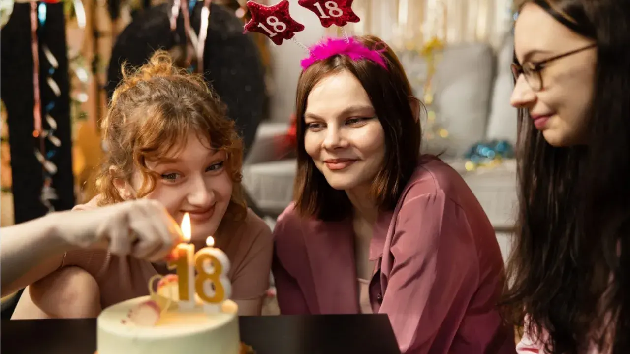 Drei junge Frauen feiern den 18. Geburtstag. Kerzen auf dem Kuchen leuchten, ein neues Kapitel beginnt, auch bezüglich Kindesunterhalt ab 18.