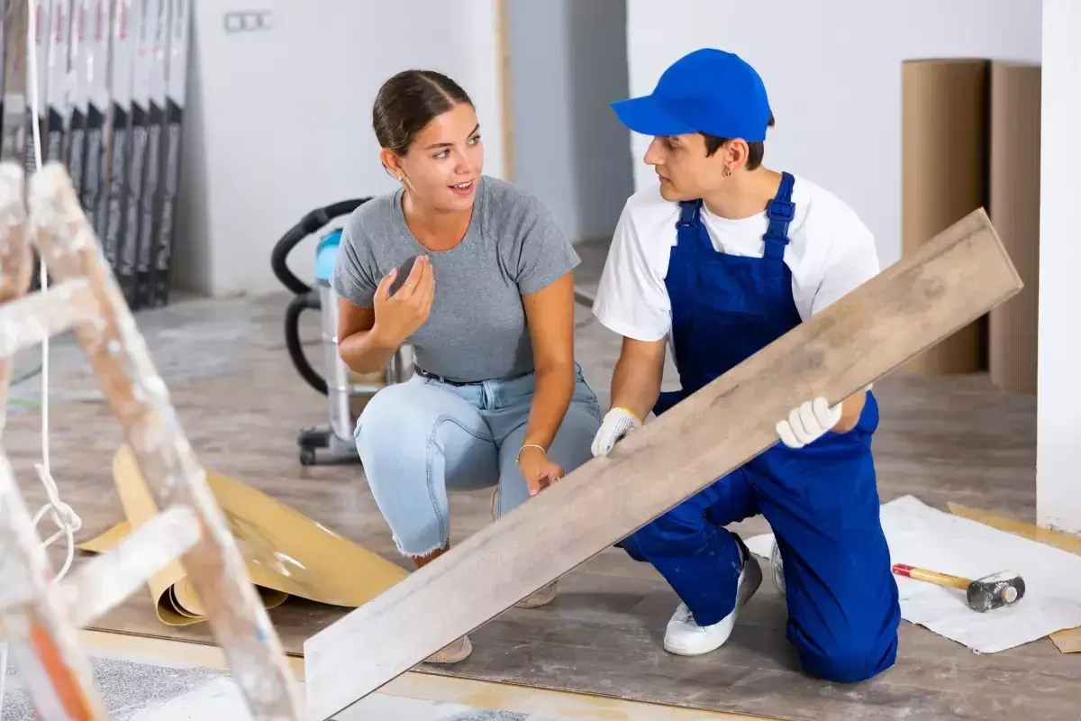 Un artisan montre une lame de parquet à une cliente. Elle s'interroge sur quels travaux peut on déduire des impôts pour ce type de rénovation.