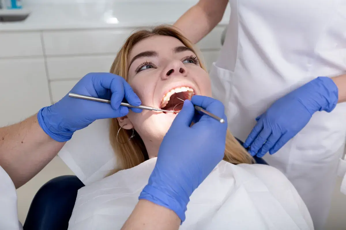 Dentysta bada zęby pacjentki. Czy plomba może wypaść? Specjalista ocenia stan uzębienia.