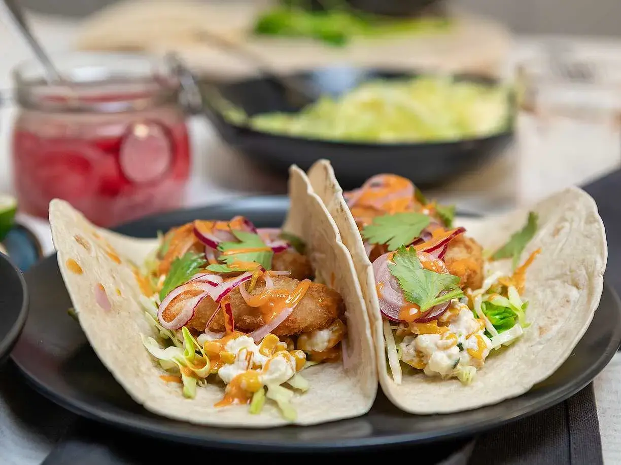Två läckra fish tacos med krispig fisk, kål, rödlök och en krämig sås. Ett perfekt recept för en snabb och god middag.