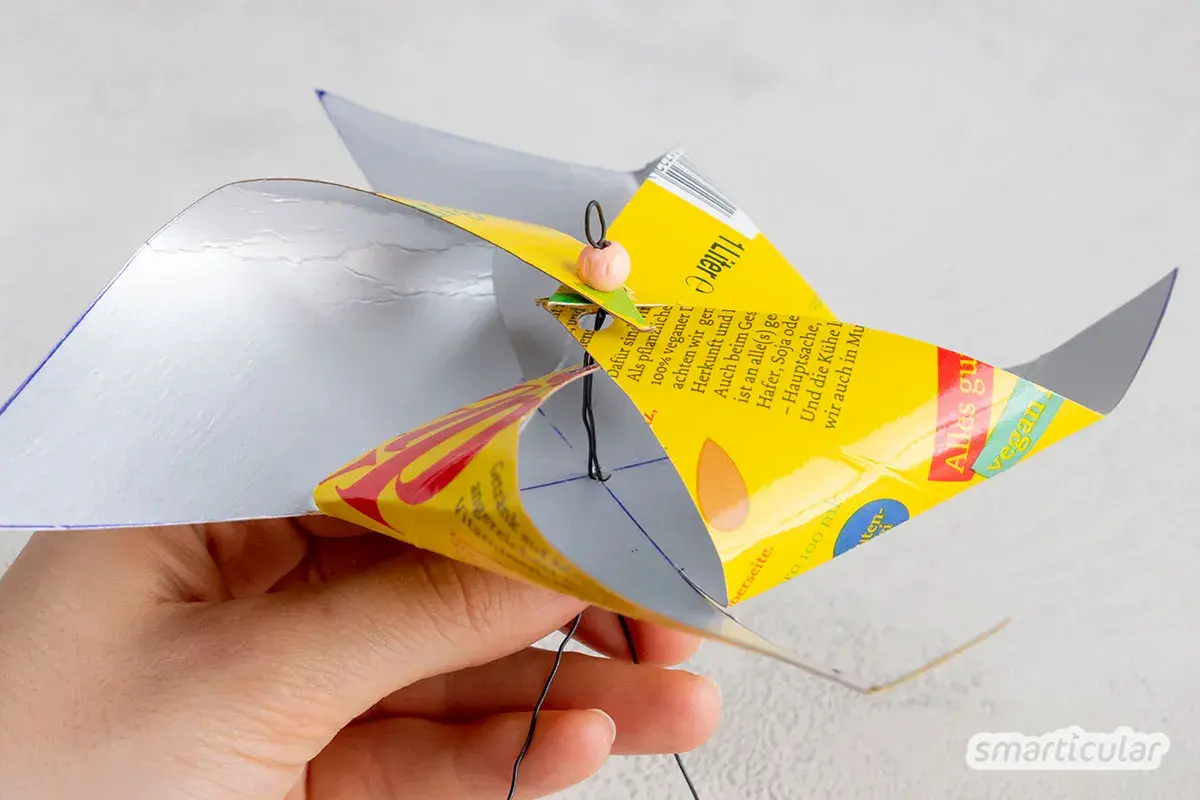 Bastelanleitung für ein Windrad: Eine Hand hält ein selbstgemachtes Windrad aus einer Getränkeverpackung, das sich dreht. Eine Vorlage zum Windrad basteln ist hier zu sehen.