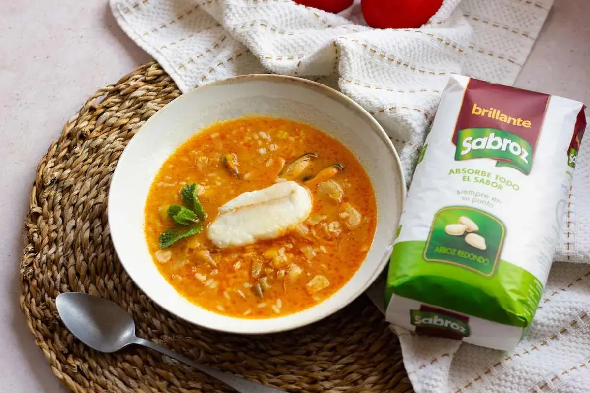 Sopa de pescado con arroz sencilla, con trozos de pescado, mejillones y arroz redondo Sabroz, decorada con menta.