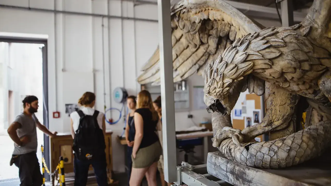 Studierende im Restaurationsstudium betrachten eine detailreiche Skulptur eines geflügelten Wesens.