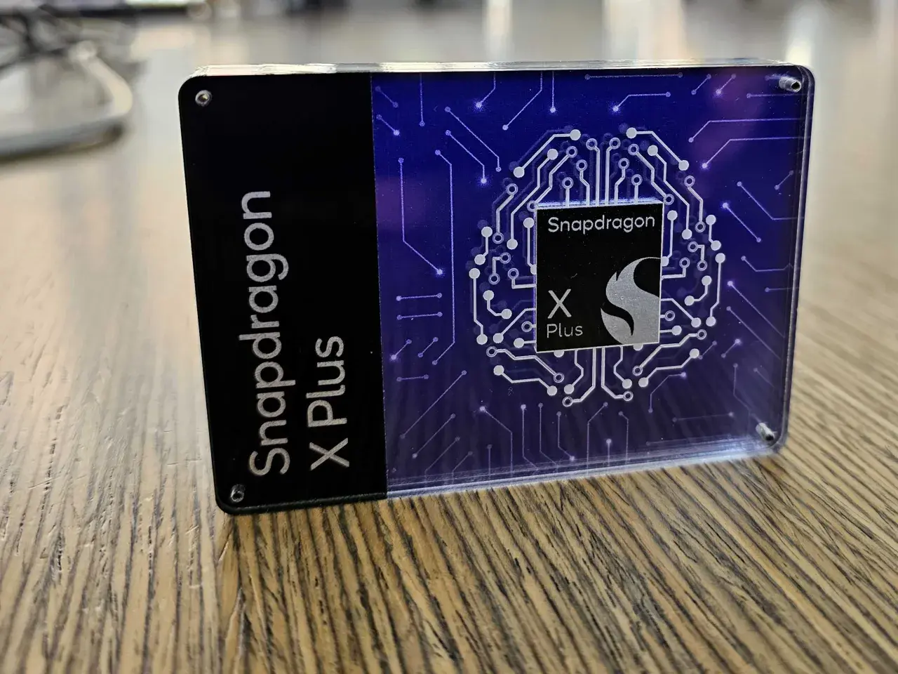 Ein transparentes Gehäuse mit dem Schriftzug "Snapdragon X Plus" und einem stilisierten Chip-Design.